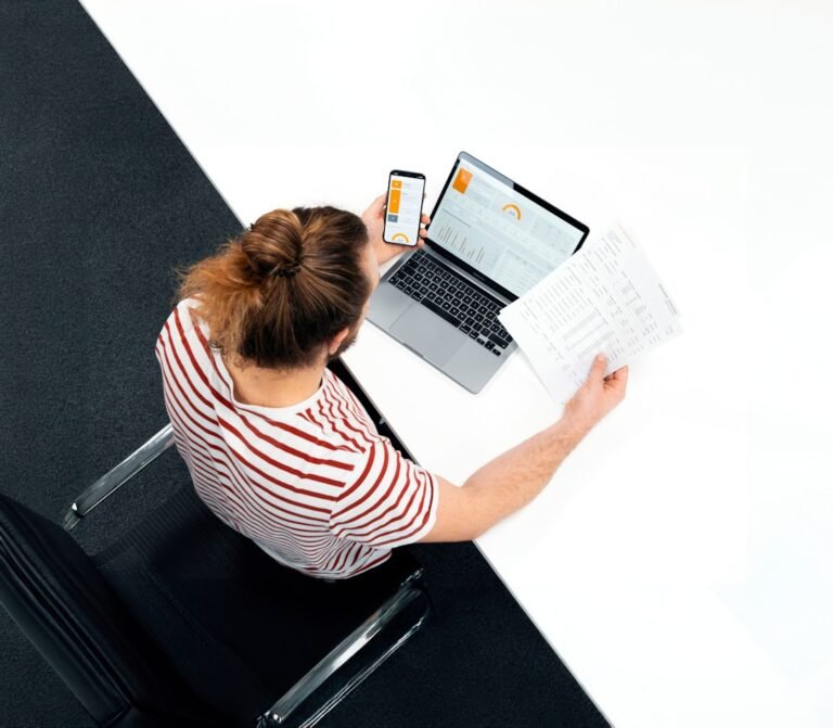 Office worker at a laptop with papers representing the hidden productivity cost of AI workslop